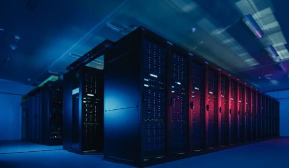Shot of Data Center With Multiple Rows of Fully Operational Server Racks. Modern Telecommunications, Cloud Computing, Artificial Intelligence, Database, Supercomputer Technology Concept. Shot in Dark with Neon Blue, Pink Lights.